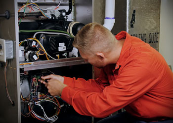 G.F. Bowman HVAC technician performing maintenance AC system.