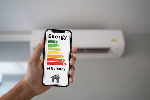 Hand holding phone showing energy efficiency ratings for air conditioners.