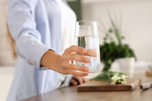 A woman holding a glass of water.